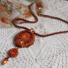 Pendentif Lady in Orange est brodé avec un cabochon en Cristal et en verre, perle goutte zébrée, rose, perles magiques, cuir vachette, calotte, chaînette et fermoir Doré pour un style contemporain